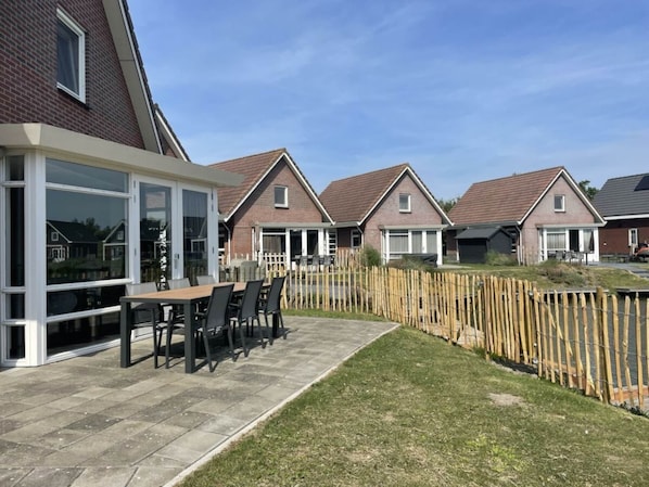 Ein Wohngebiet mit Häusern, einer Terrasse mit Tisch und Stühlen und einem Holzzaun.
