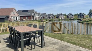 Eine Terrasse mit Tisch und Stühlen, ein Holzzaun und Häuser im Hintergrund.
