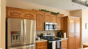 Eine Küche mit Holzschränken, Edelstahlgeräten und einer Fliesenrückwand.