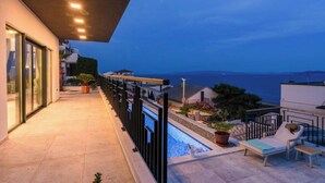 Un balcon avec une piscine, des chaises longues et une vue sur la mer.