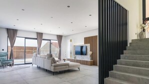 Un salon moderne avec un canapé, un téléviseur et un escalier.