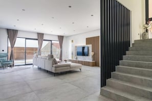 A modern living room with a sofa, a TV, and a staircase. - Villa Adriatica (Okrug Gornji, Trogir,)