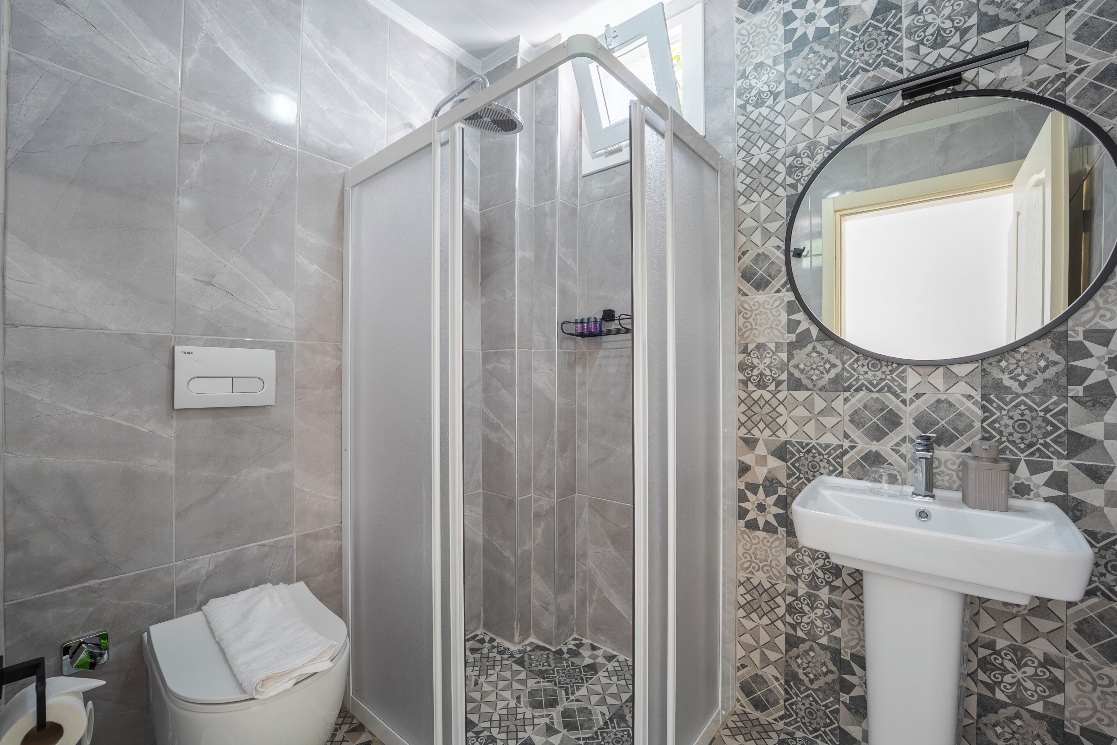 Un baño con cabina de ducha, lavamanos y espejo.