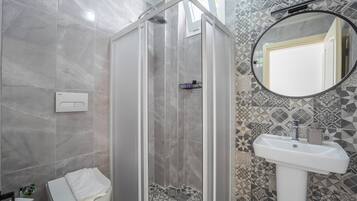 Un baño con cabina de ducha, lavamanos y espejo.