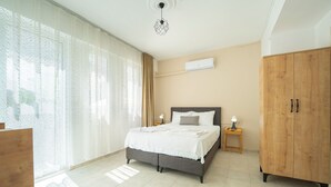 Un dormitorio con cama, armario, mesita de noche y ventana con cortinas.