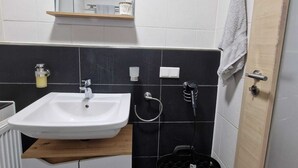 A bathroom with a white sink, a mirror, a towel rack, a black basket, and a door. - Vacation Rental in Lüchtringen (Höxter)
