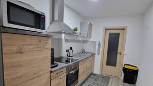 A modern kitchen with wooden cabinets, stainless steel appliances, and a microwave. - Vacation Rental in Lüchtringen (Höxter)