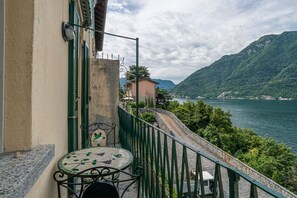 Een balkon met een tafel en stoel, met uitzicht op een meer en bergen.