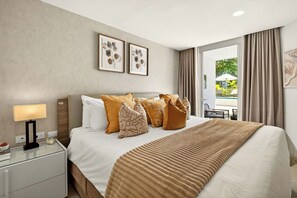 Habitación de hotel con cama, mesita de noche, lámpara y vistas a un espacio exterior.