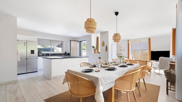 A modern kitchen with white cabinets, a dining area with a table set for four, and a large window. - 4-Bedroom Villa with Private Pool & Spa for 8, Carquefou/Nantes (Carquefou)