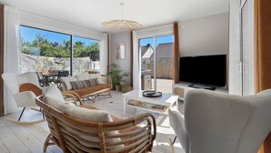 A spacious living area with a television, wicker furniture, and large windows. - 4-Bedroom Villa with Private Pool & Spa for 8, Carquefou/Nantes (Carquefou)