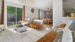 A modern living room with a white sofa, a coffee table, and a dining area with a table and chairs. - 4-Bedroom Villa with Private Pool & Spa for 8, Carquefou/Nantes (Carquefou)