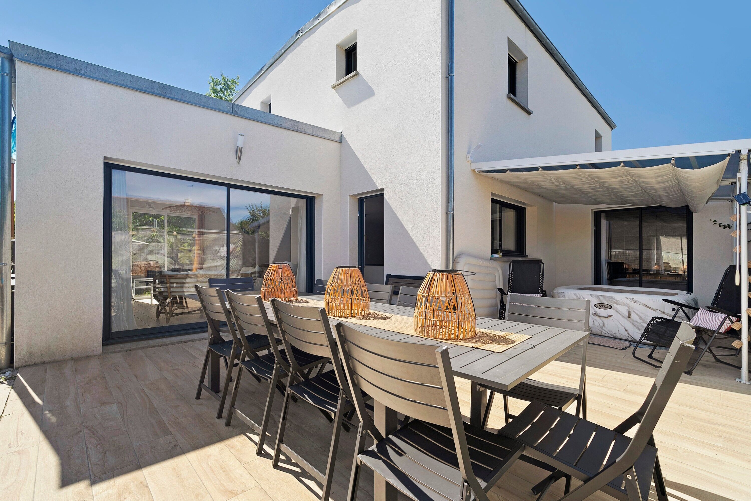 A modern outdoor patio with a dining table, chairs, and a barbecue area.