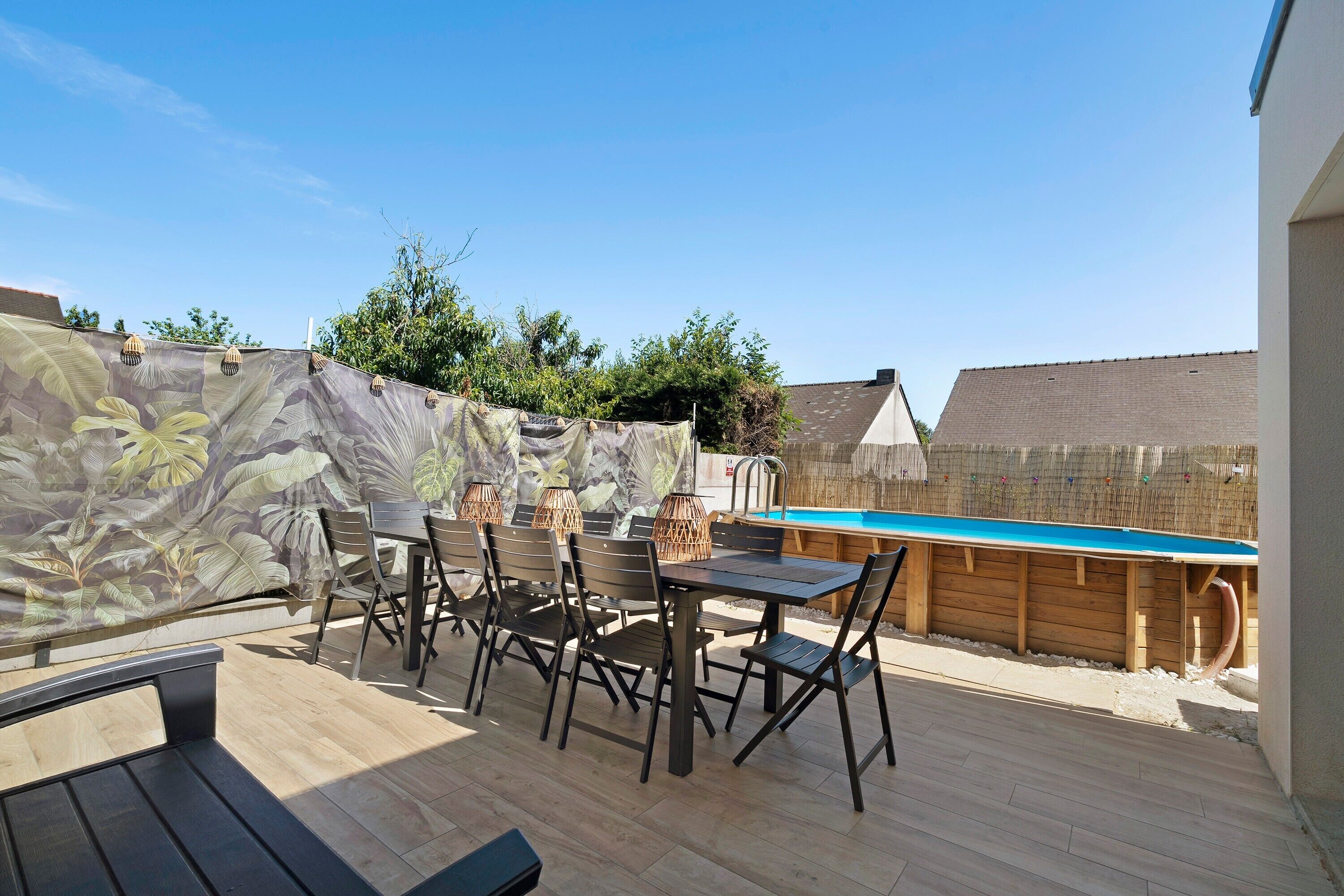 Patio esterno con piscina, un pontile in legno e un tavolo con sedie.