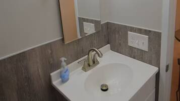 Un bagno con un lavandino bianco, uno specchio e un porta asciugamani.