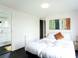 Ein modernes Schlafzimmer mit einem Bett, einem Schminktisch, einem Spiegel und einem Bild an der Wand.