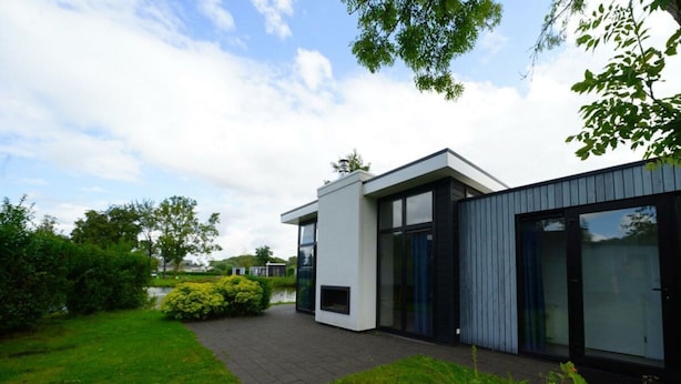 A modern building with a flat roof, large windows, and a paved pathway leading to the entrance. - Cube Maximaal 4 (Halfweg)