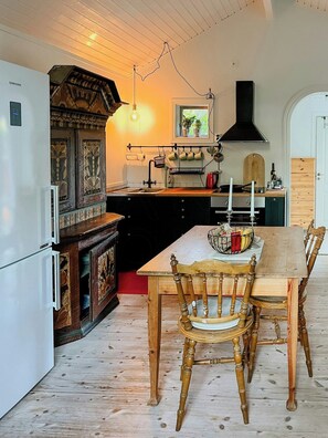 Eine Küche mit einem Holztisch, Stühlen, einem Herd und einem Kühlschrank.