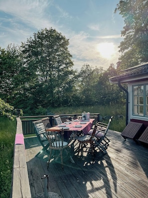 Eine Terrassensitzgelegenheit im Freien mit Esstisch und Stühlen, mit Blick auf einen üppigen Garten.