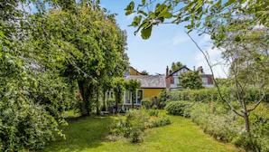 Ein Garten mit einem Haus, Bäumen und blauem Himmel.