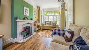Ein Wohnzimmer mit Kamin, einer Couch, einem gemusterten Teppich und einer grünen Akzentwand.