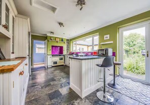 Uma cozinha moderna com ilha central, área de jantar com banquetas e vista para o exterior.