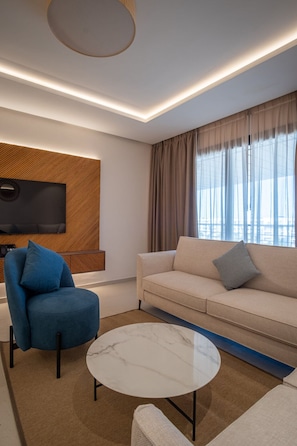 A modern living room with a sofa, armchair, and a round coffee table.