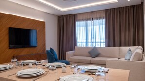 A modern dining area with a wooden table set for a meal, a sofa, and a TV mounted on the wall.
