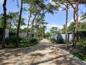 A pathway lined with trees leading to a row of modern, single-story buildings. - Holiday Home in Otterlo With Terrace (Otterlo)
