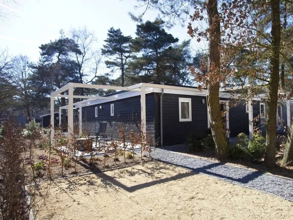 A modern cabin with a covered patio area, surrounded by trees and a gravel path. - Holiday Home in Otterlo With Terrace (Otterlo)