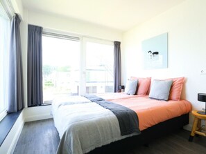 A bedroom with a bed, a window, and a painting on the wall. - Villa Meerzicht 10 (Nijkerk)