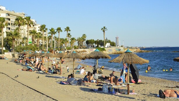 A beach with people sunbathing, umbrellas, and palm trees. - Flisvos Beach Retreat (ΑΘΗΝΑ)