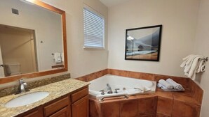 A bathroom with a sink, mirror, bathtub, and towels. - 1-bedroom condo in Sedona Arizona (Sedona)