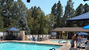 A swimming pool with lounge chairs and umbrellas, surrounded by trees. - 1-bedroom condo in Sedona Arizona (Sedona)