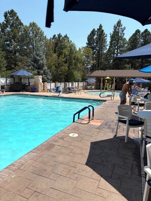 A swimming pool with lounge chairs and umbrellas, surrounded by trees. - 1-bedroom condo in Sedona Arizona (Sedona)