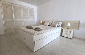 Ein Schlafzimmer mit Bett, Nachttischen, einem Kleiderschrank und einem Beistelltisch.