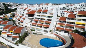A high-rise hotel with multiple balconies, a central swimming pool, and a view of the surrounding cityscape. - Sunset View Albufeira (53) (Albufeira)