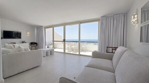 A modern living room with a sofa, a TV, and a balcony with a view of the sea. - Sunset View Albufeira (53) (Albufeira)