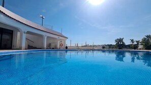 Ein Schwimmbecken mit klarem, blauem Wasser, ein Gebäude mit rotem Dach und ein klarer Himmel.