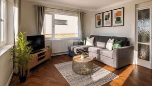 A living room with a sofa, television, and a plant. - Amazing Location - Free Parking - Beach Opposite! (Bournemouth)