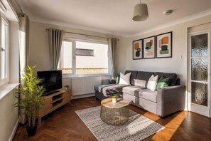 Un salon avec un canapé, une télévision et une plante.