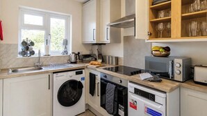 Une cuisine compacte équipée d’un lave-linge, d’un four, d’un micro-ondes et d’un égouttoir à vaisselle.