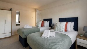Une chambre d’hôtel avec deux lits, une armoire, un miroir et une table de chevet avec une lampe.