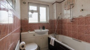 Une salle de bain comprenant des toilettes, un lavabo, une baignoire et une fenêtre.