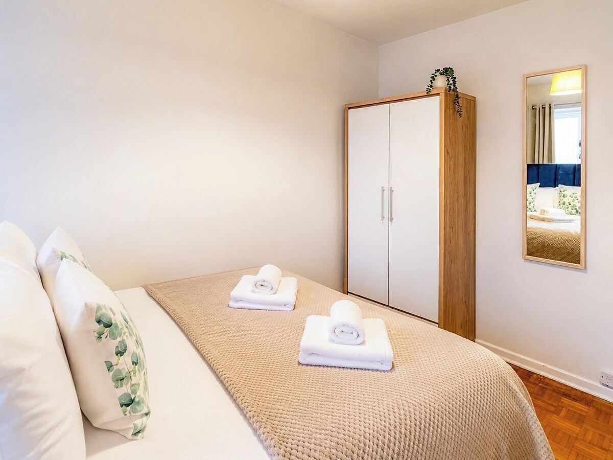 A bedroom with a bed, a wardrobe, a mirror, and two towels on the bed.