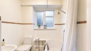 Et badeværelse med toilet, badekar og bruser.