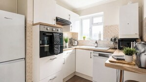 Uma cozinha moderna com armários brancos, forno embutido, micro-ondas e pia.