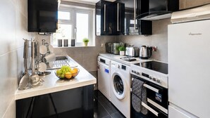 Cocina compacta con lavadora, estufa y refrigerador.