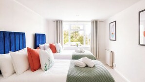 Habitación de hotel con dos camas, una ventana con cortinas, un radiador y un cuadro en la pared.