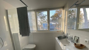 Et badeværelse med toilet, brusebad og vask.